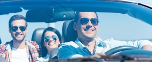 Group of happy people enjoying road trip in their convertible