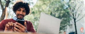 Young man working with laptop and smartphone outdoors