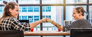 Young hipster couple fist bumping in victory after they learned about filing state taxes for free.