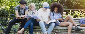 College students hanging out studying on park bench