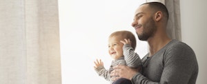 Man holding his infant son as they look out of the window