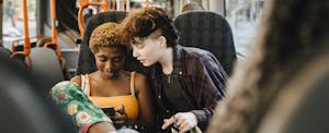 Two teenagers sitting and talking together on a bus