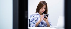 Young woman using her smartphone while working in an office