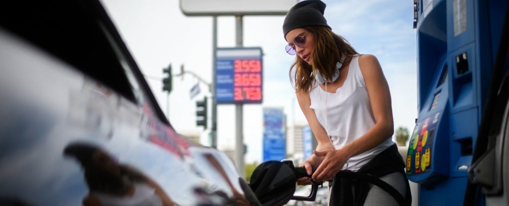 Young woman pumping gas after finding out how gas credit cards work