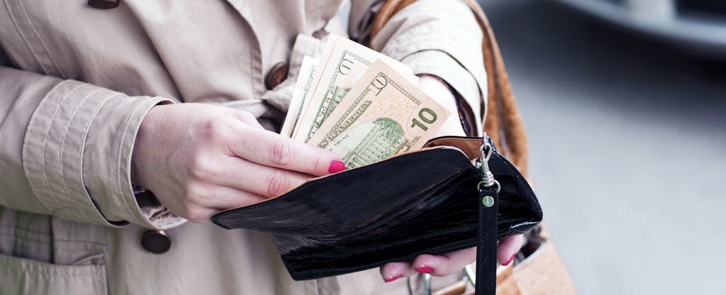 Woman counting cash from her wallet and contemplating claiming her unclaimed money