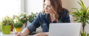 Woman sitting next to a computer and reading about if you should you pay the IRS with a credit card?