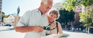 Couple looking at map while traveling with Premier Rewards Gold Card from American Express or Chase Sapphire Preferred Card