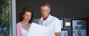 A mature couple looking at architectural plans together at home, wondering what mortgage points are.