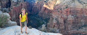 Young woman standing in front of a beautiful canyon while debating if she should get the discover it vs chase freedom