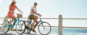 Young couple bicycling on a boardwalk and talking about how to get a credit card