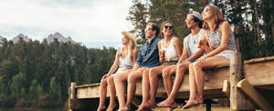 A group of friends sitting on a dock and discussing the 4 financial keys to adulting