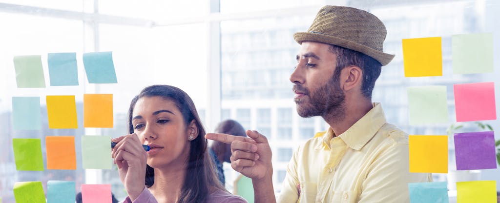 Man pointing at a Post-It note that a coworker is writing on full of little-known credit cards tips