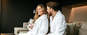 Couple lounging in bathrobes in a fancy hotel suite after maximizing the benefits of the Ritz-Carlton Rewards Credit Card