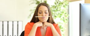 Young woman balancing a pencil on her upper lip while looking thoughtful