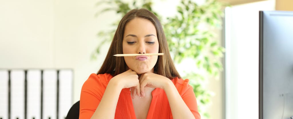 Young woman balancing a pencil on her upper lip while wondering, "Will a balance transfer hurt my credit score?"