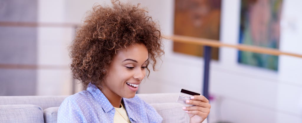 Woman smiling and looking at her Amazon credit card