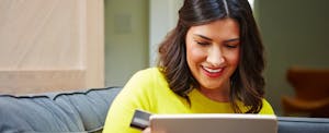 Smiling woman looking at a laptop with the best cash back credit cards for people with fair, good, and excellent credit