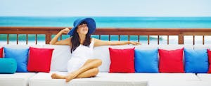 Young woman relaxing on a colorful couch in front of the ocean