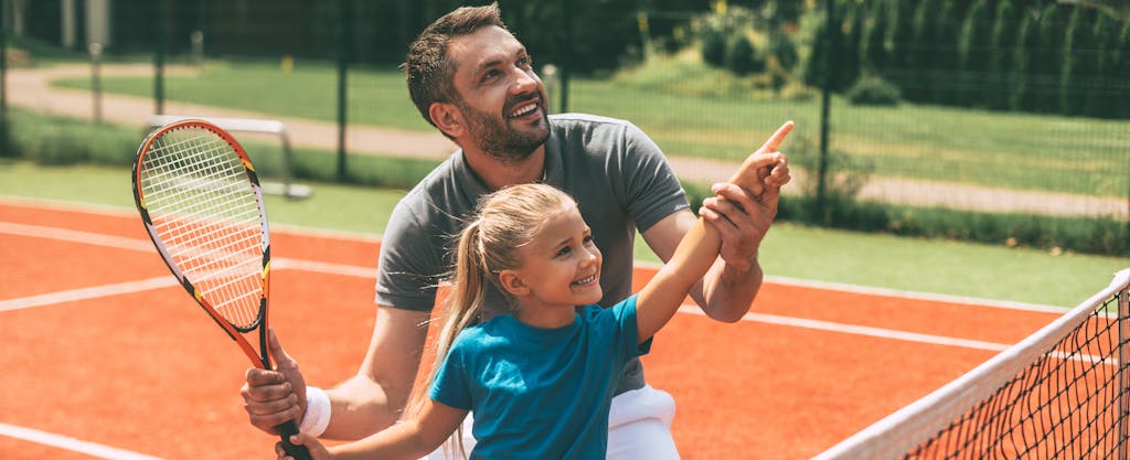 Dad teaching his daughter how to play tennis after buying her a racket using a Dick's Sporting Goods credit card