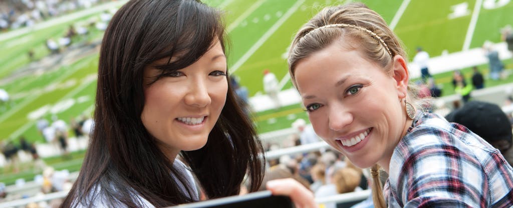 Two young women at an NFL game after using their NFL Extra Points Credit Card