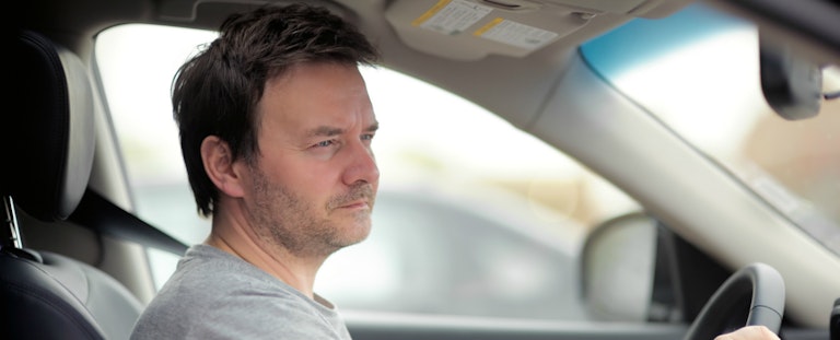 Man sits in his car, wondering how to get out of his upside down car loan