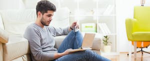 Man looks at his laptop and considers applying for a Wells Fargo Secured Card