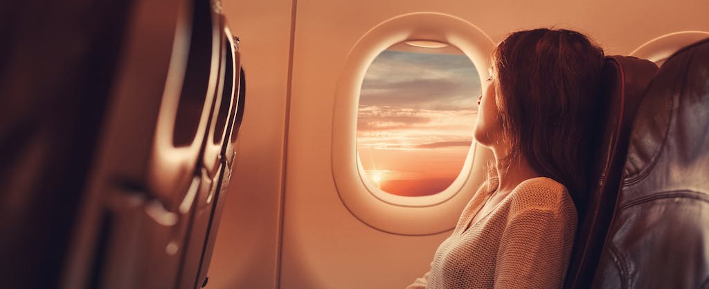 Woman in airplane looking through the window and contemplating if she should get the Gold Delta SkyMiles Credit Card or the Platinum Delta SkyMiles Credit Card