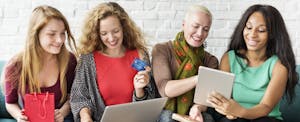 Group of women sitting on a couch and shopping online while comparing paypal credit cards