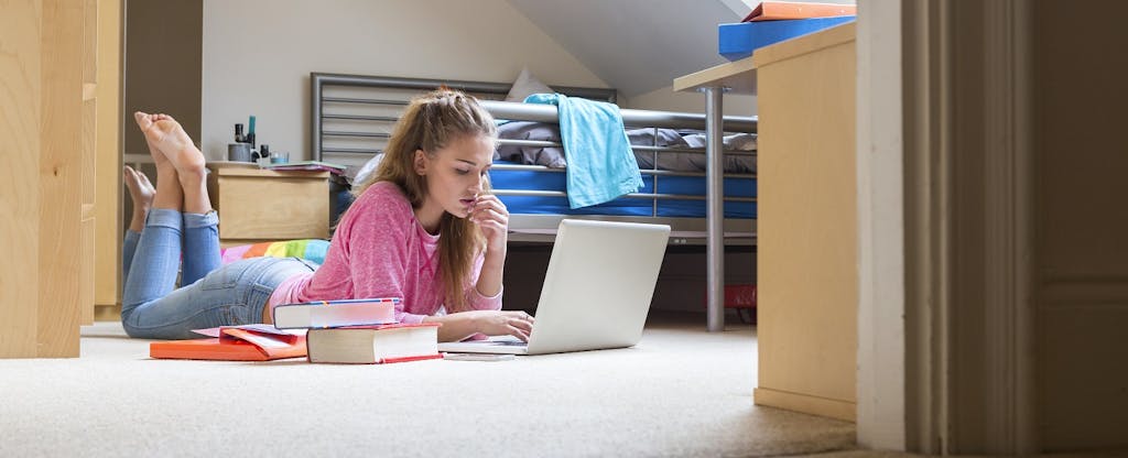 College student checks for tax tips on her laptop in her dorm room