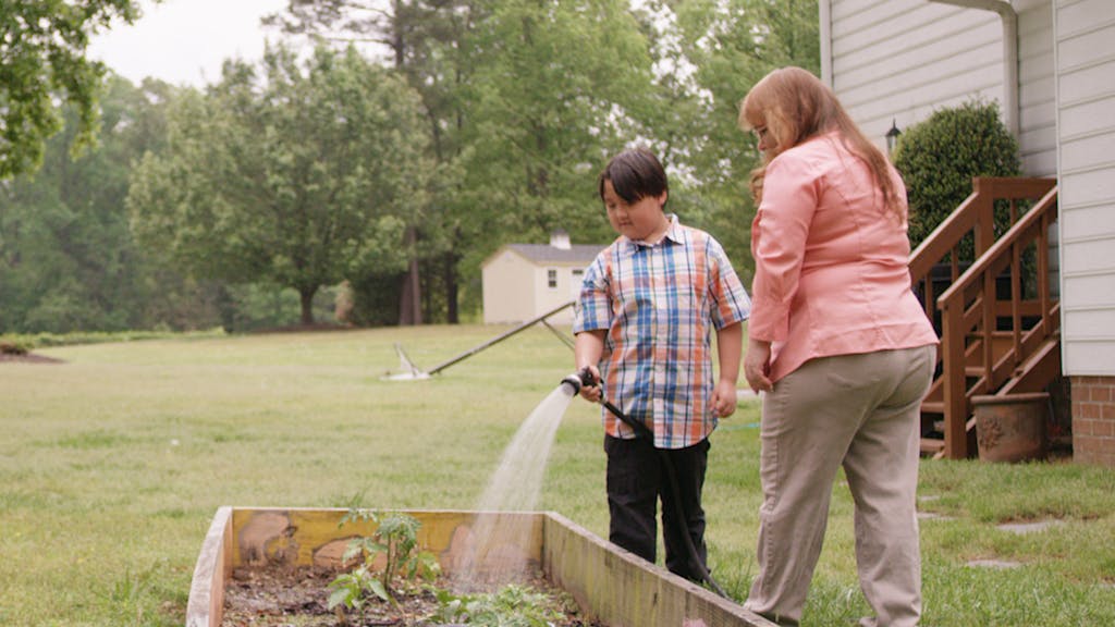 Donna and her grandson water the garden