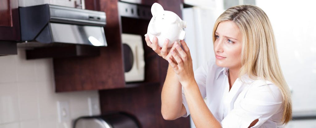 Unhappy young blonde mom emptying her family piggy bank while waiting for her tax refund.
