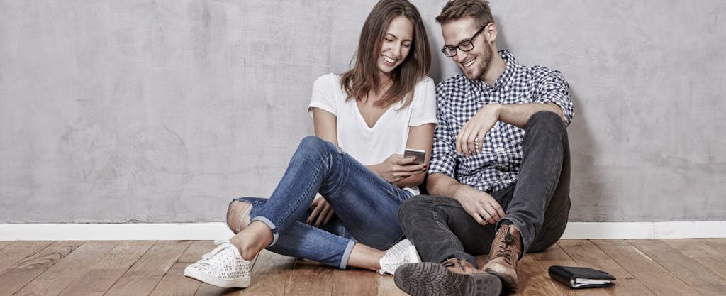 Happy young couple sitting on the floor reviewing steps they can take to maximize their tax refund.