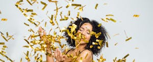 Young woman tossing confetti to celebrate the New Year and her financial New Year's resolutions