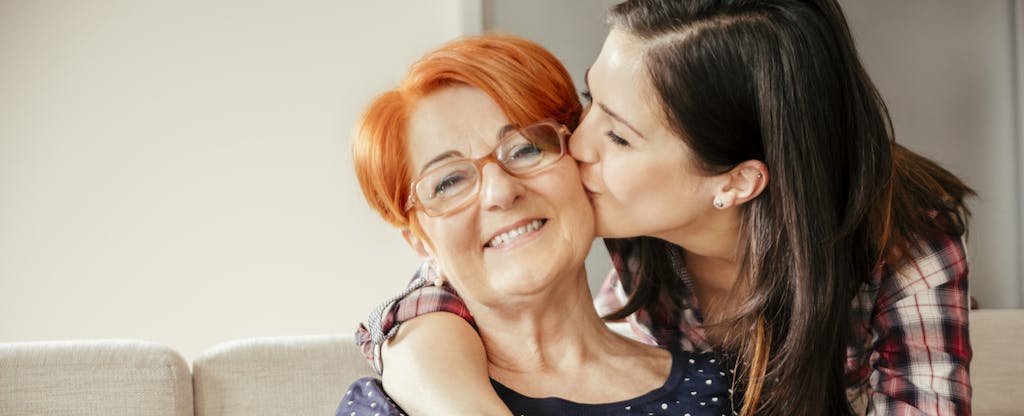 Happy adult daughter embracing and kissing mother