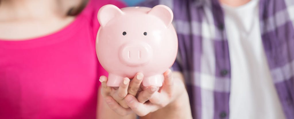 Young couple holding a piggy bank where they plan to stash the money they save with the Saver's Credit tax credit on their federal income taxes.
