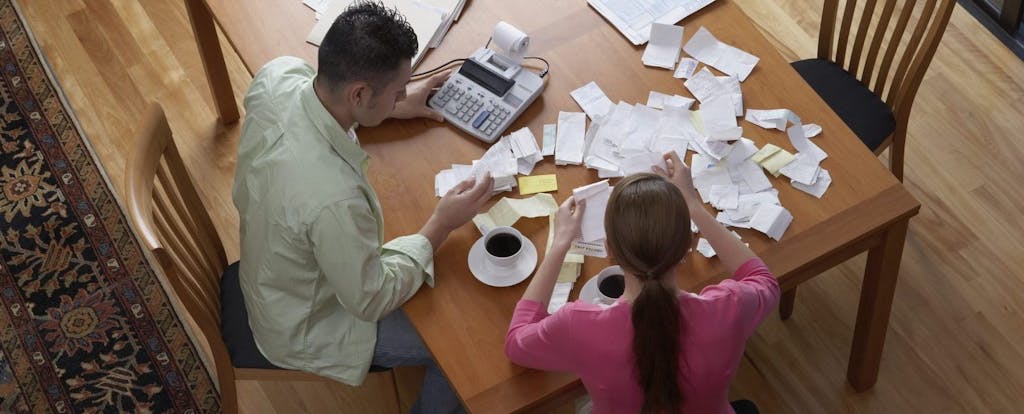 Couple going through receipts on their dining room table, looking for best tax deductions to take.