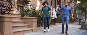 African-American couple walking down a city street, swinging their little daughter between them.