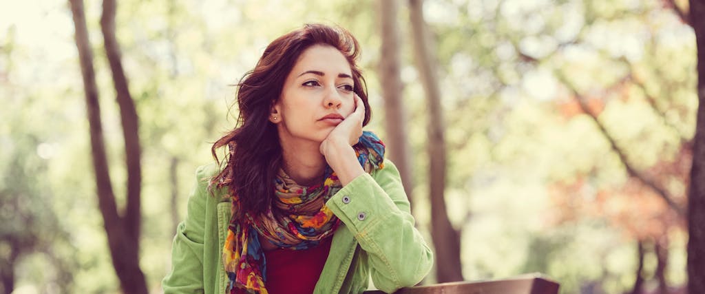 Thoughtful woman in the park thinking about debt forgiveness and wondering if she can get it