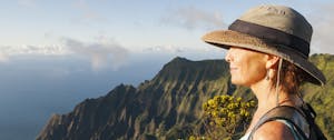 A woman looks out at the dramatic, time-worn landscape at Kalalau Lookout on Kauai, Hawaiian Islands