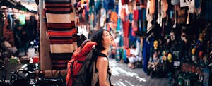 A female backpacker is waling around an open-air market