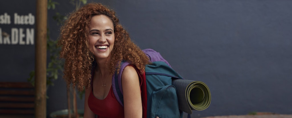 Young woman smiling, with travel backpack on
