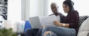 Couple with laptop discussing financial paperwork in living room