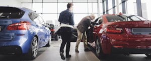 Car shoppers look at autos in dealer showroom.