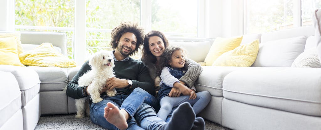 Family with dog sitting together in living room. Did they get their FICO scores free?