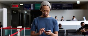 Man using smartphone at airport boarding gate.