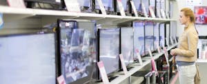 Young woman shopping for a flatscreen TV in the electronics department and wondering if she can put the purchase toward her sales tax deduction.