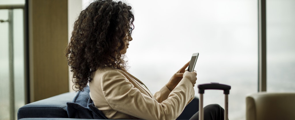 Businessman using mobile phone in Priority Pass lounge at LAS airport