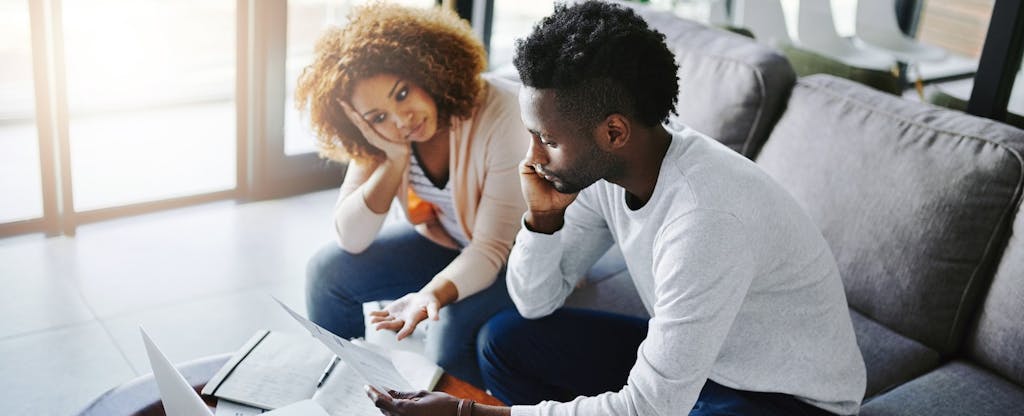 Young African-American couple reviewing their finances and considering how they'll budget to repay their 401(k) loans since tax reform gave borrowers more time.