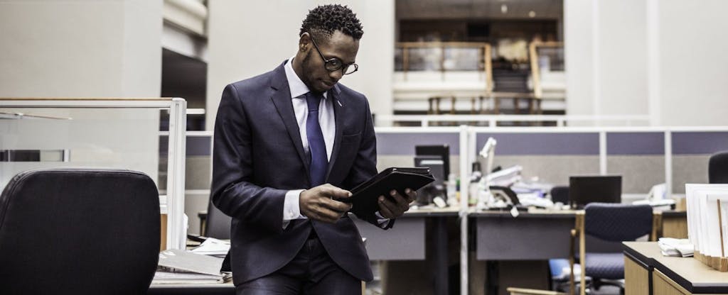 Young African-American businessman using his smartphone to learn more about the capital gains tax rate on his investments.