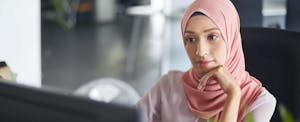 Muslim businesswoman working on a laptop and contemplating how the new pass-through deduction might apply to her federal income tax.